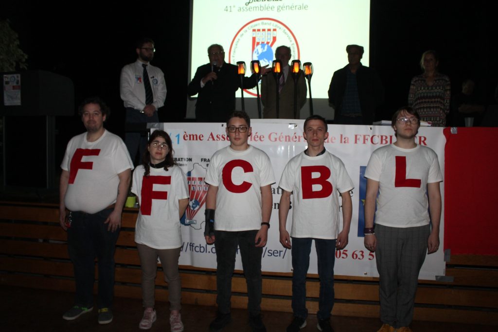 Cinq personnes portant un t-shirt blanc, chacune avec une lettre différente formant « FFCBL », posant ensemble pour la photo lors de la 40ᵉ Assemblée Générale de la FFCBL/SER à Montagnac.
