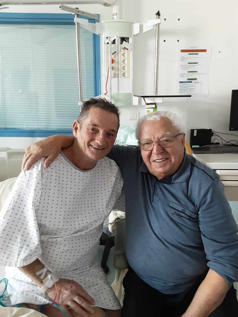 André Antonio, président de la FFCBL/SER, et Erik, assis côte à côte lors d’une visite à l’hôpital, partageant un moment d’amitié et de soutien.